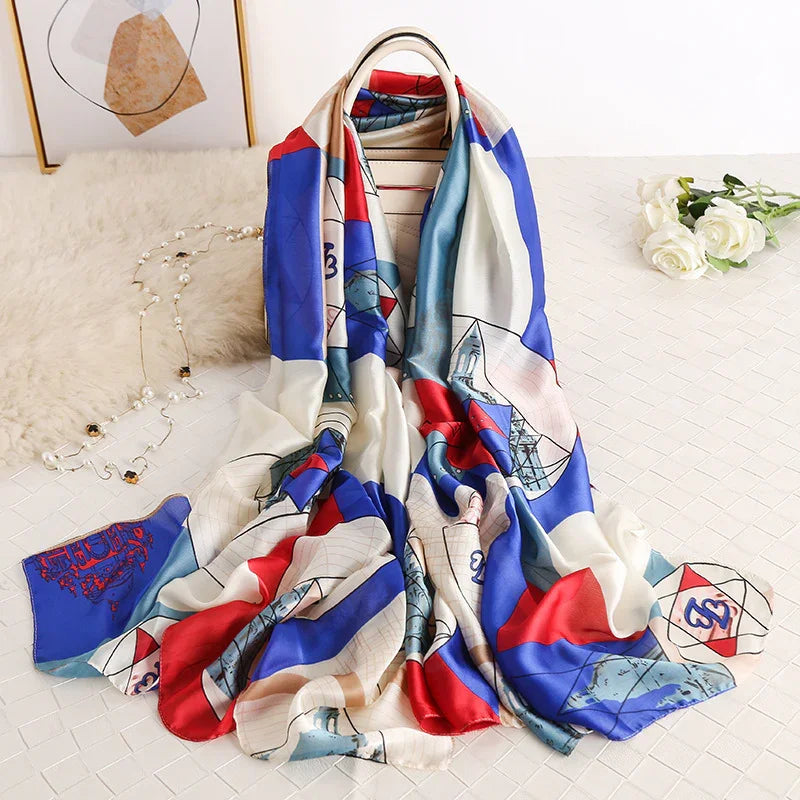 Colorful silk scarf with red, blue, and white geometric and architectural patterns displayed on white surface