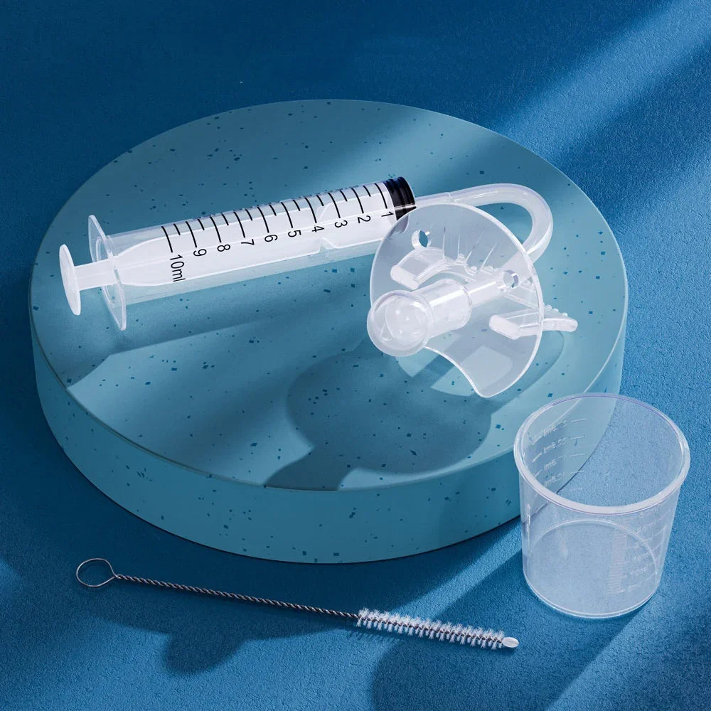 Medical syringe feeding tube set with transparent syringe, cap, measuring cup, and cleaning brush on blue surface