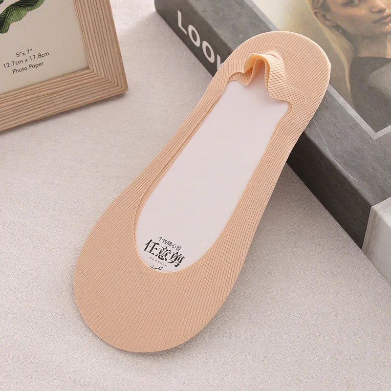 Beige no-show liner sock with ribbed texture on light surface near photo frame and book