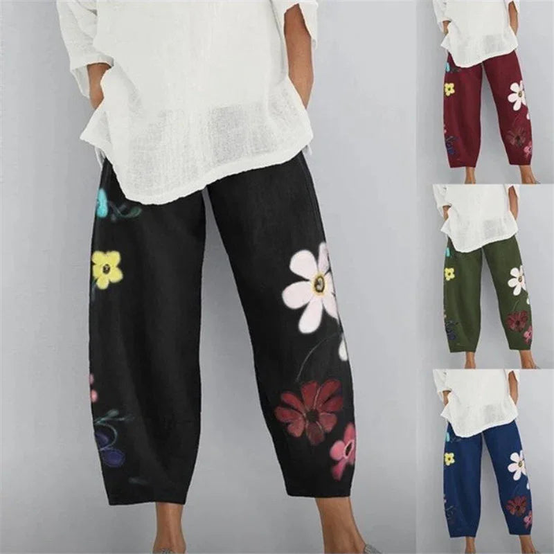Women wearing loose floral print pants in black, burgundy, green, and navy with white tops