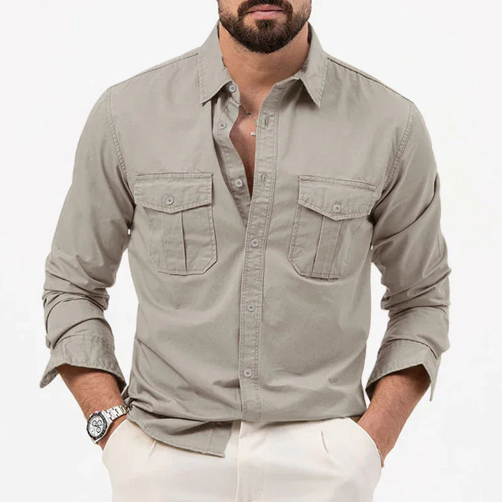 Man wearing beige casual button-up shirt with chest pockets and rolled sleeves, paired with white pants