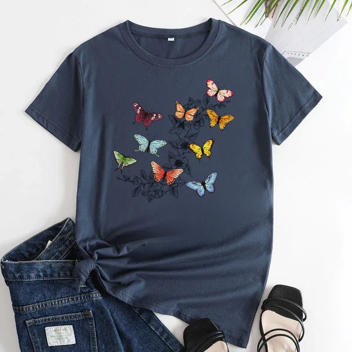 Navy blue t-shirt with colorful butterfly print paired with denim jeans and black strappy sandals