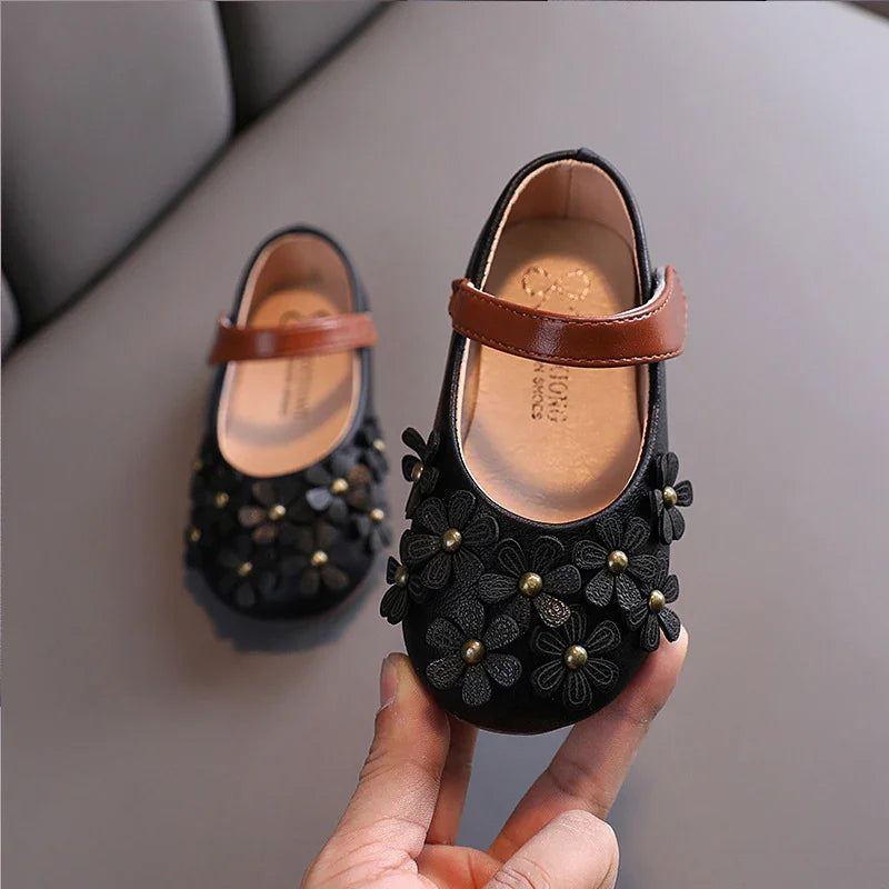 Black baby girl Mary Jane shoes with brown straps and decorative flower embellishments
