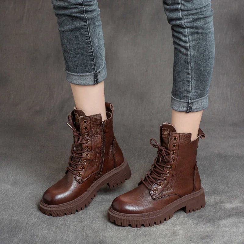 Brown leather combat boots with side zipper and rugged sole worn with rolled-up gray jeans