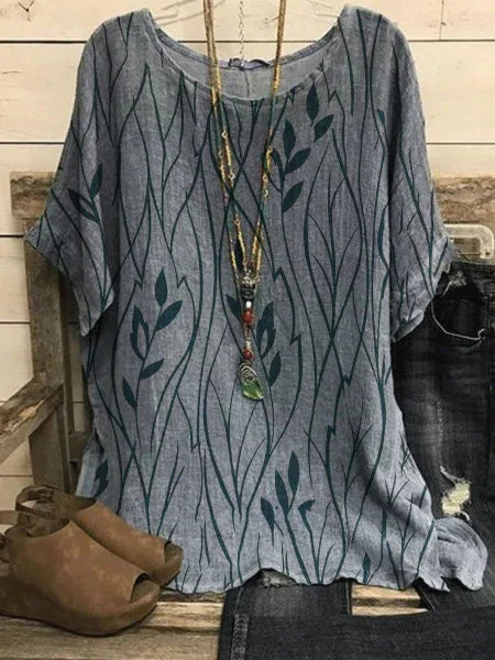 Blue casual short-sleeve top with leafy vine print paired with brown open-toe shoes and layered necklaces