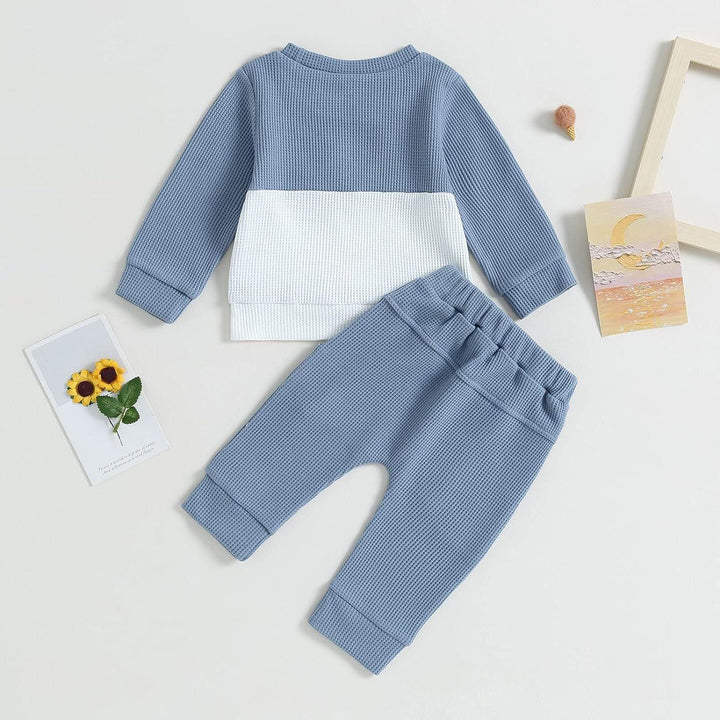 Blue and white waffle knit baby outfit with long sleeves and matching pants on light background
