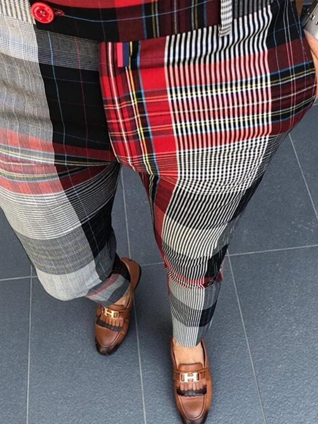 Men's plaid patchwork trousers paired with brown leather loafers on gray tile floor