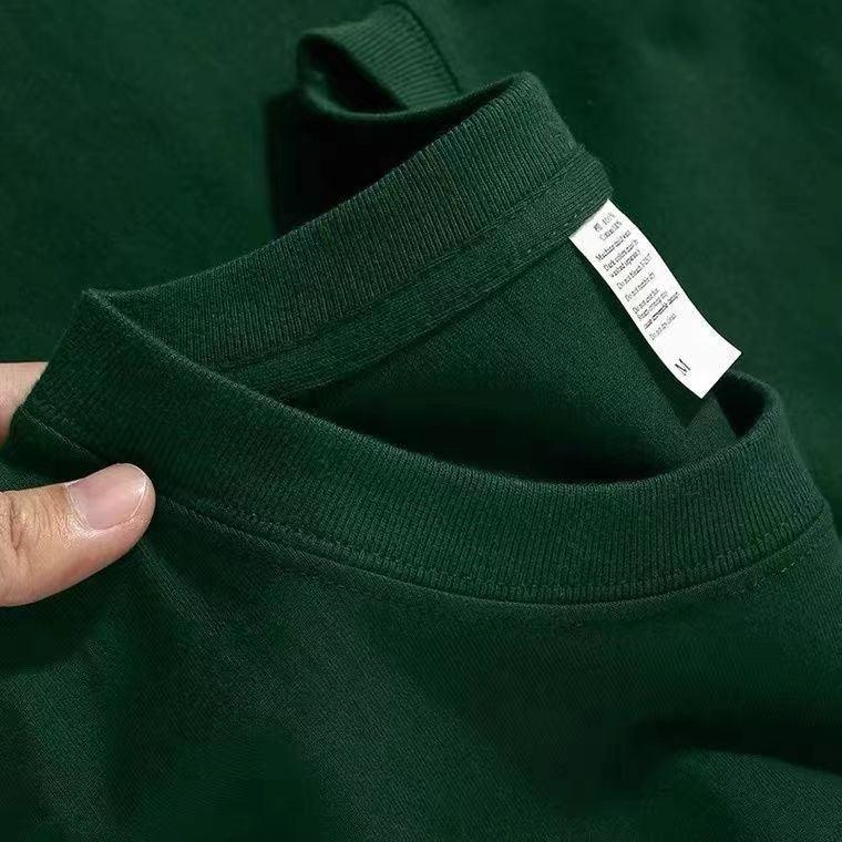Close-up of dark green cotton t-shirts with visible tags and folded collars