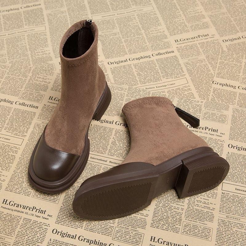 Brown suede ankle boots with dark brown leather toe caps and block heels on newspaper print background