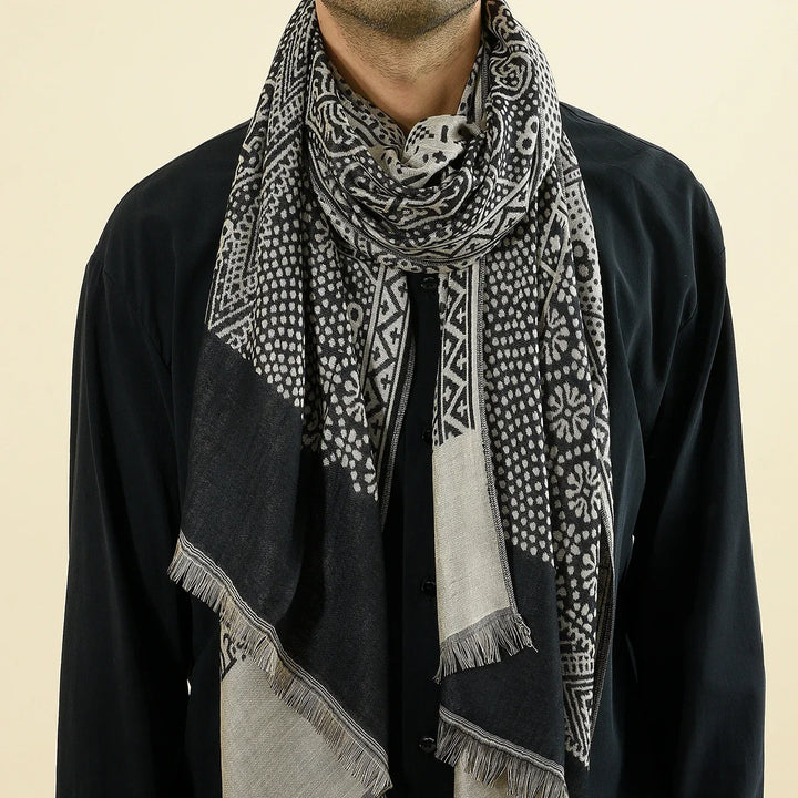 Close-up of a man wearing a black shirt and a black and white patterned fringed scarf