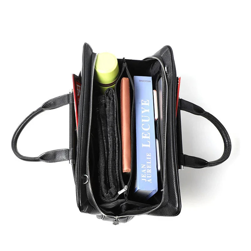 Top view of black leather handbag with a green bottle, brown wallet, folded black scarf, and a blue book inside