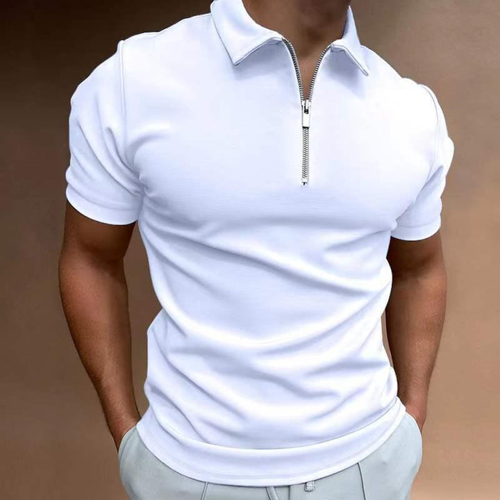Man wearing fitted white short-sleeve polo shirt with silver zipper collar, hands in light gray pants pockets