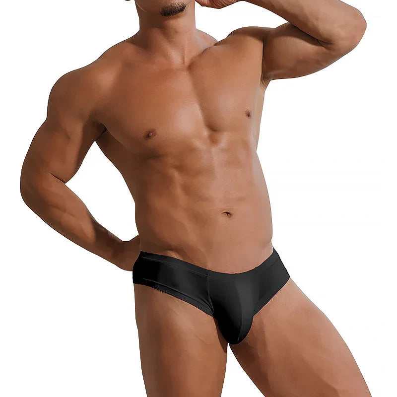 Muscular male torso wearing black low-rise briefs on white background