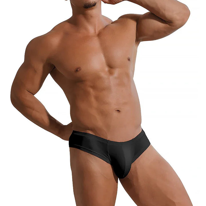 Muscular male torso wearing black low-rise briefs on white background