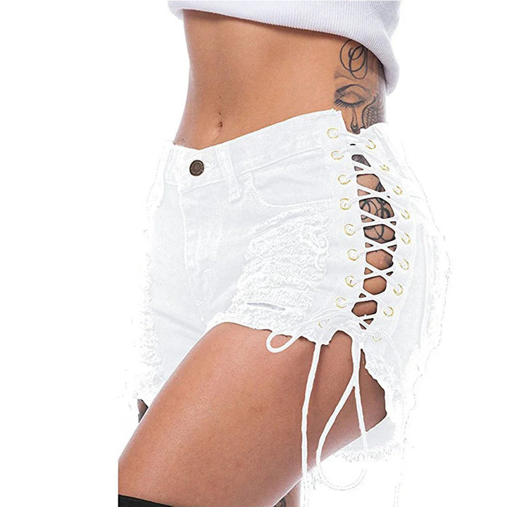 Close-up of a woman wearing white distressed denim shorts with side lace-up detail and tattoo visible
