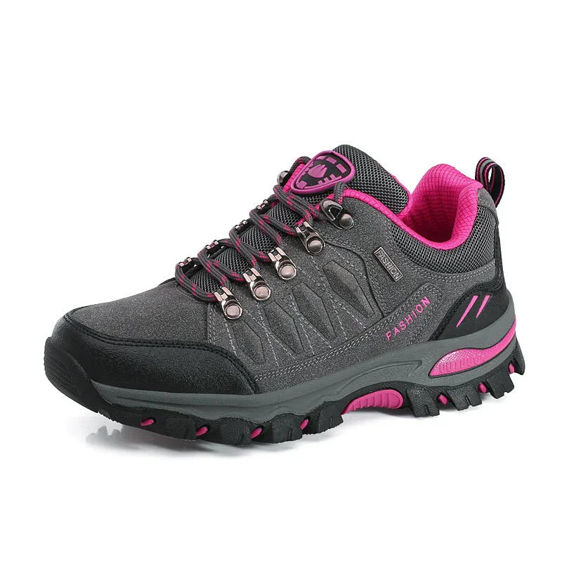 Gray and pink women's hiking shoe with rugged sole and metal eyelets on white background
