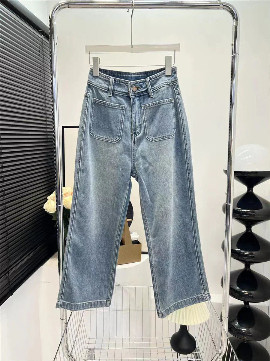 Light wash denim wide-leg jeans with front patch pockets hanging on a rack in a modern interior