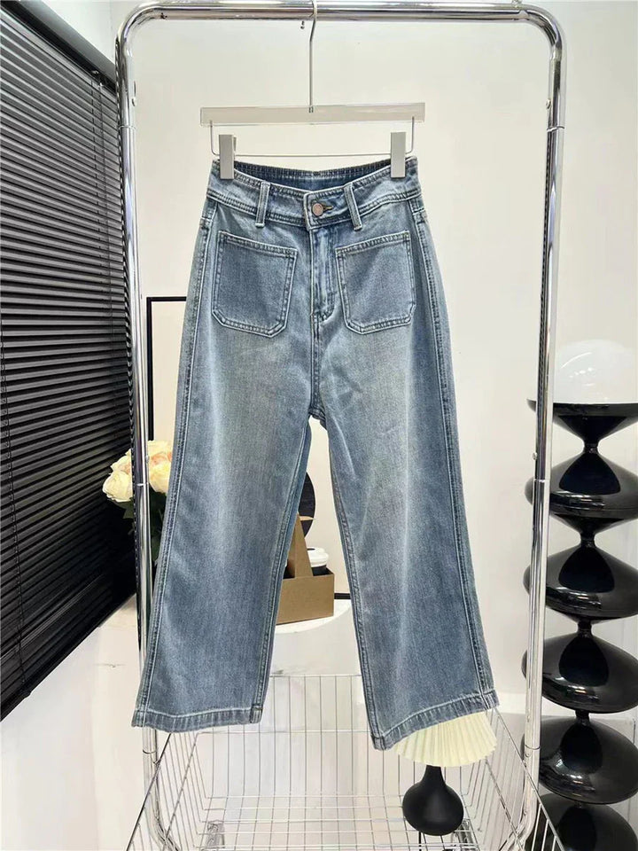 Light wash denim wide-leg jeans with front patch pockets hanging on a rack in a modern interior