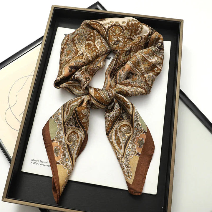 Brown paisley patterned silk scarf tied in a bow inside a black gift box