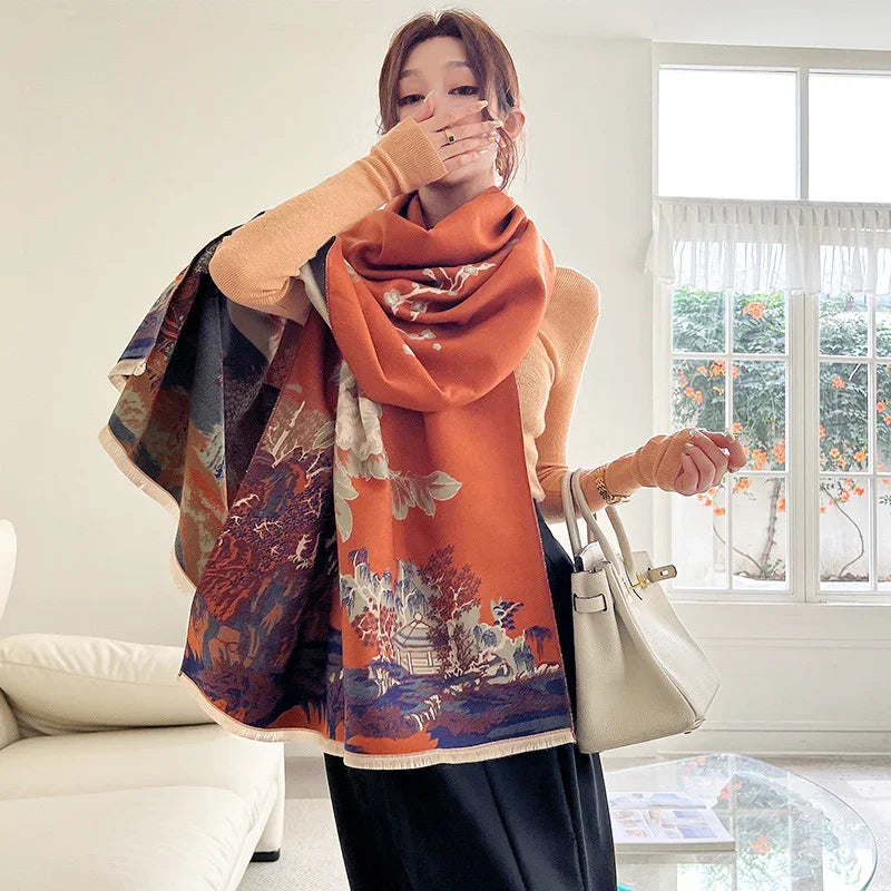 Woman wearing a large orange floral scarf, beige sweater, holding white handbag indoors near window