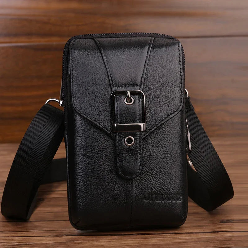 Black leather crossbody bag with front buckle detail and adjustable strap on wooden surface