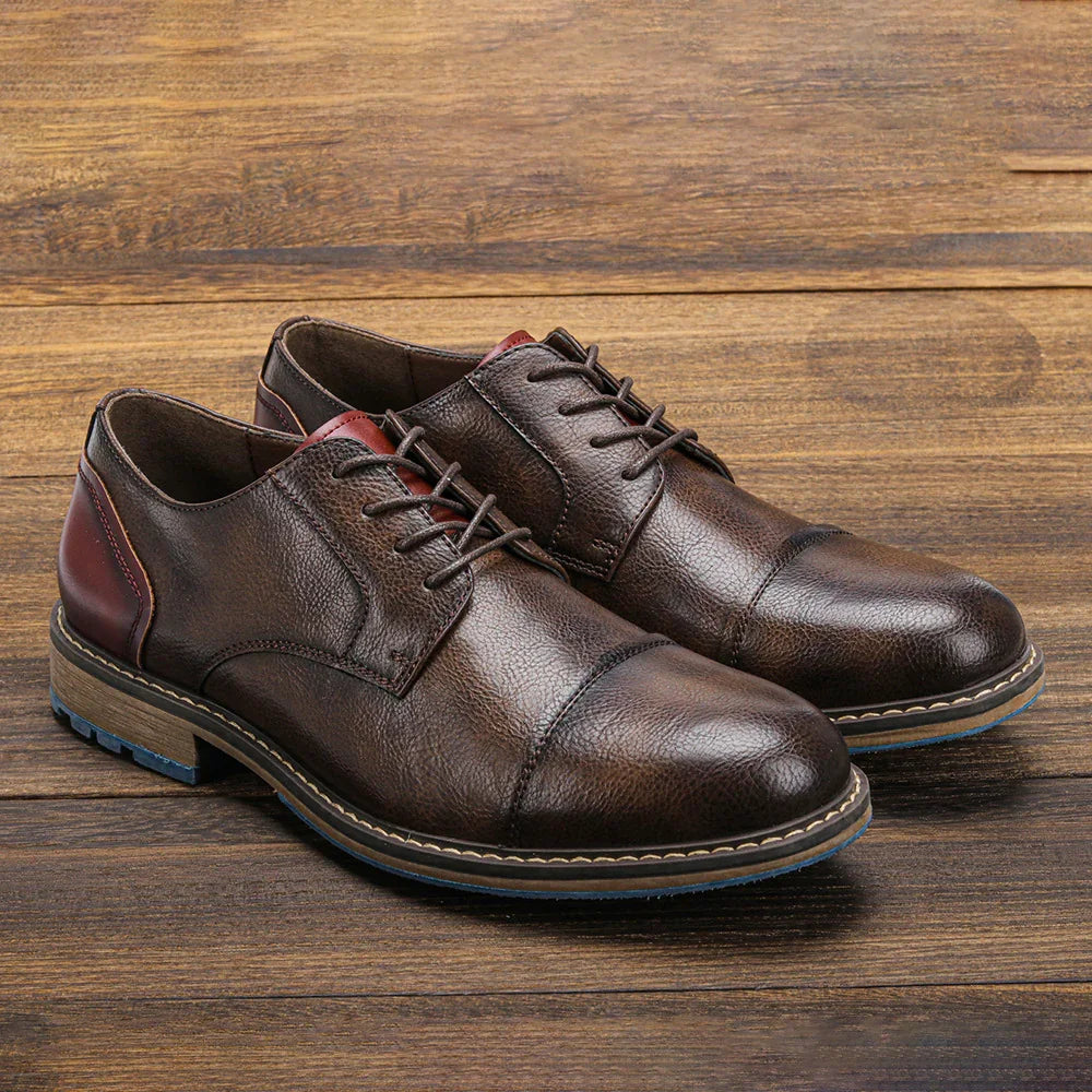 Pair of brown leather men's dress shoes with laces on wooden floor
