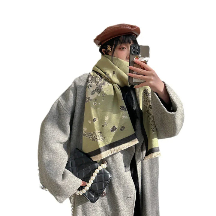 Woman wearing grey wool coat, olive floral scarf, brown beret, holding quilted black purse and taking selfie