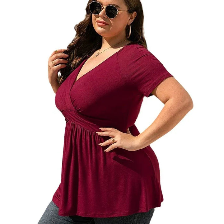 Plus size woman wearing burgundy wrap top with short sleeves and V-neck, styled with sunglasses