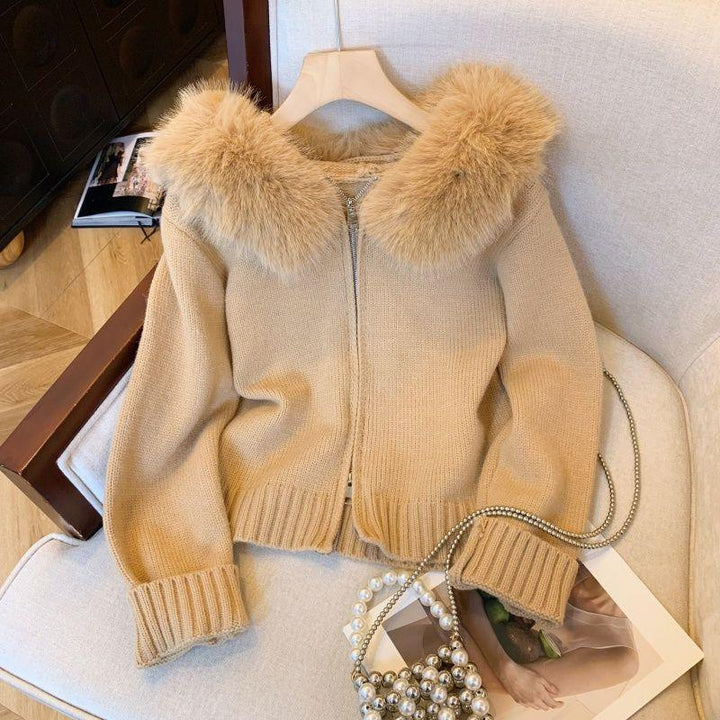 Beige knit cardigan with fluffy fur collar on wooden hanger, pearl chain bag on cream sofa