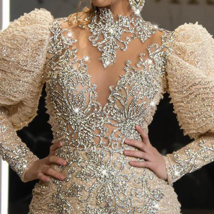 Close-up of an elegant beige gown with puffed sleeves and intricate sparkling rhinestone embroidery