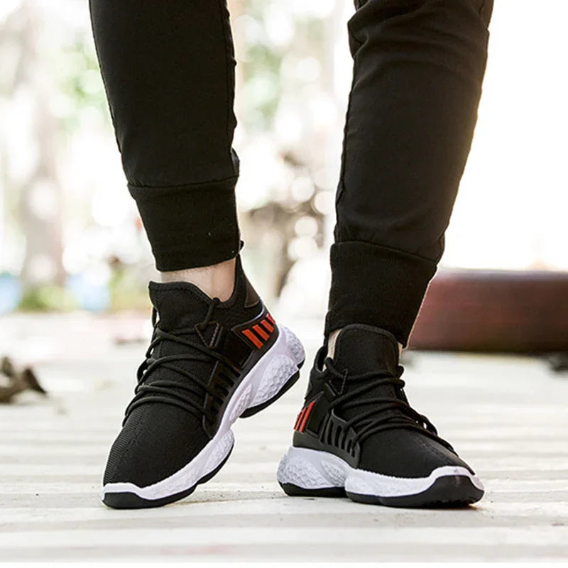 Black athletic sneakers with white textured sole and red accents worn with black jogger pants
