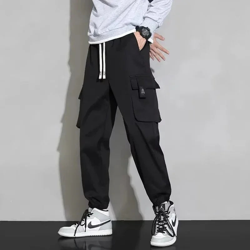 Man wearing black cargo jogger pants with white drawstring and white Nike Air Jordan sneakers