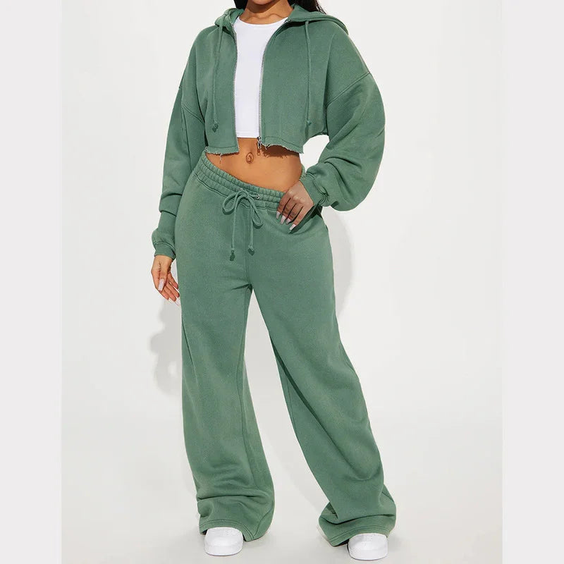 Woman wearing sage green cropped hoodie and matching wide-leg sweatpants with white sneakers