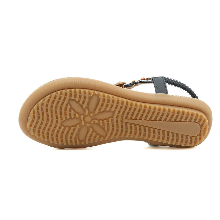 Bottom view of a women's sandal with tan rubber sole featuring a flower tread pattern