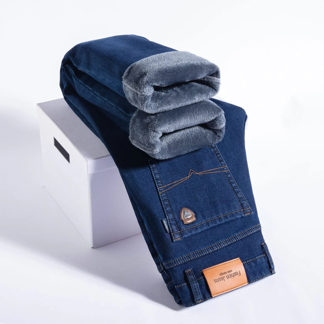 Folded blue jeans with soft gray fleece lining against a white background