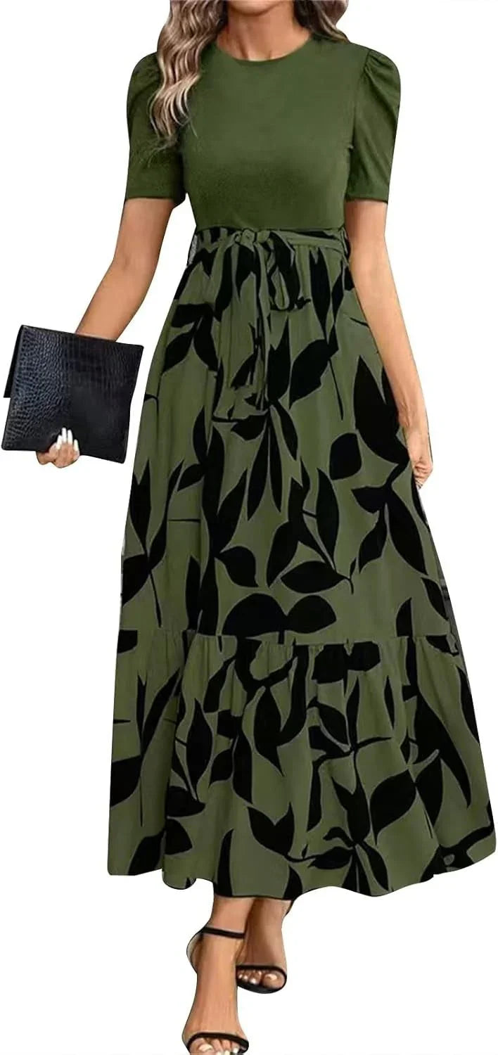 Woman wearing olive green maxi dress with black leaf print and short sleeves holding black clutch