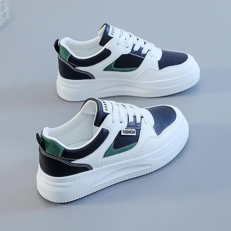 White sneakers with black and green accents and thick white soles on a gray background