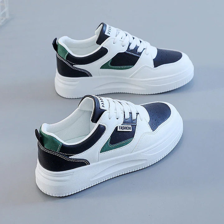 White sneakers with black and green accents and thick white soles on a gray background