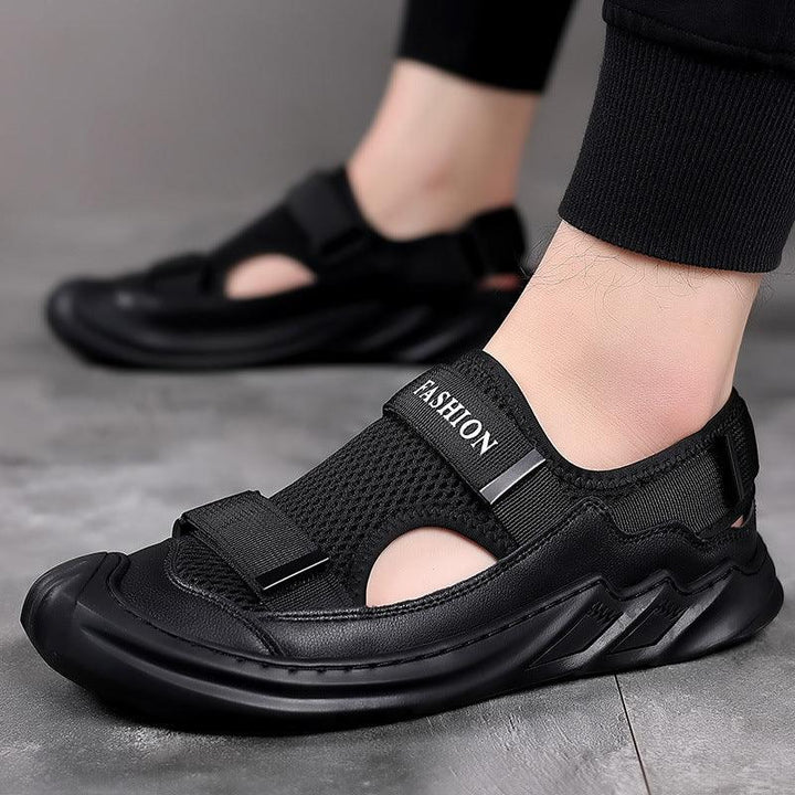 Black mesh casual sandals with velcro strap, worn indoors on a gray floor.