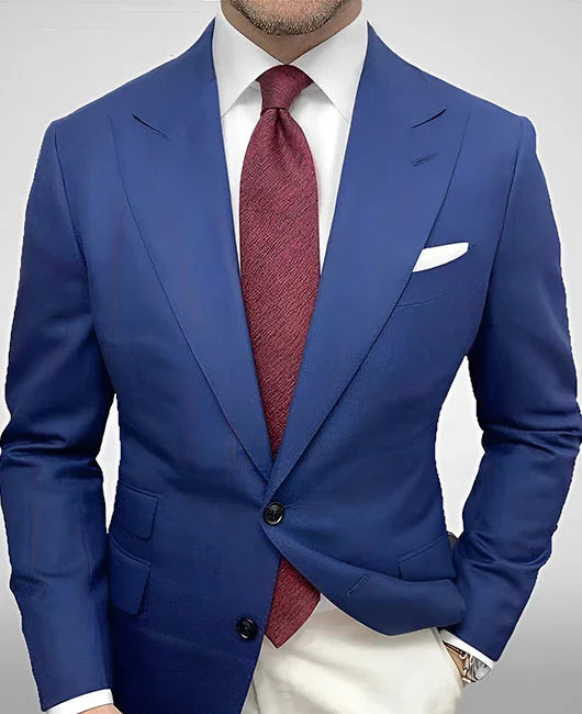 Man wearing a tailored blue blazer with white shirt and red textured tie, styled with pocket square