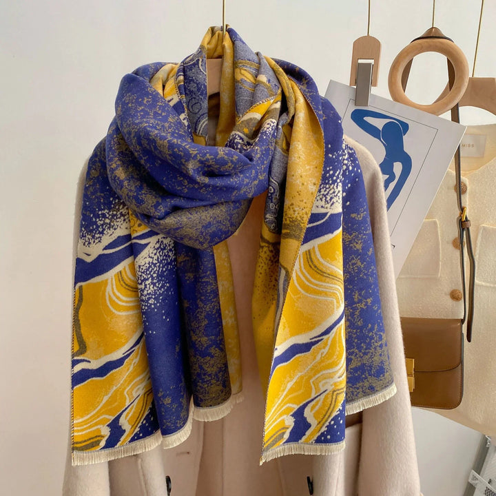 Blue and yellow abstract patterned scarf on beige coat with wooden hangers and brown leather bag