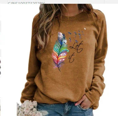 Woman wearing brown sweatshirt with colorful feather and 'Let it' text, holding flowers