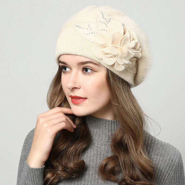 Woman wearing cream wool beret with floral embellishment and grey ribbed sweater