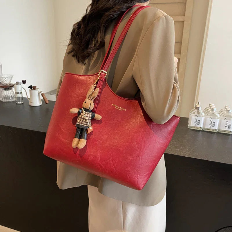 Woman carrying red leather tote bag with cute bunny keychain in modern indoor setting