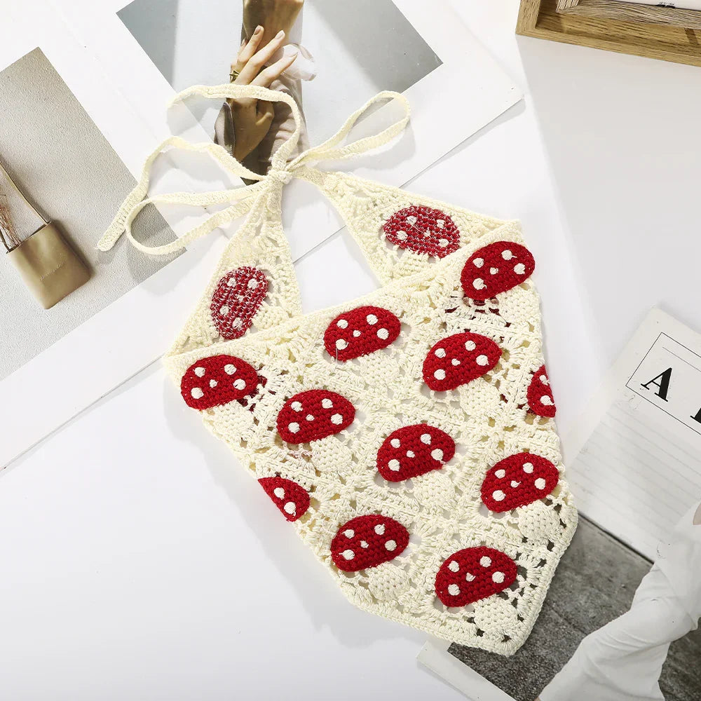 Handmade cream crochet halter top with red and white mushroom patterns on a white surface