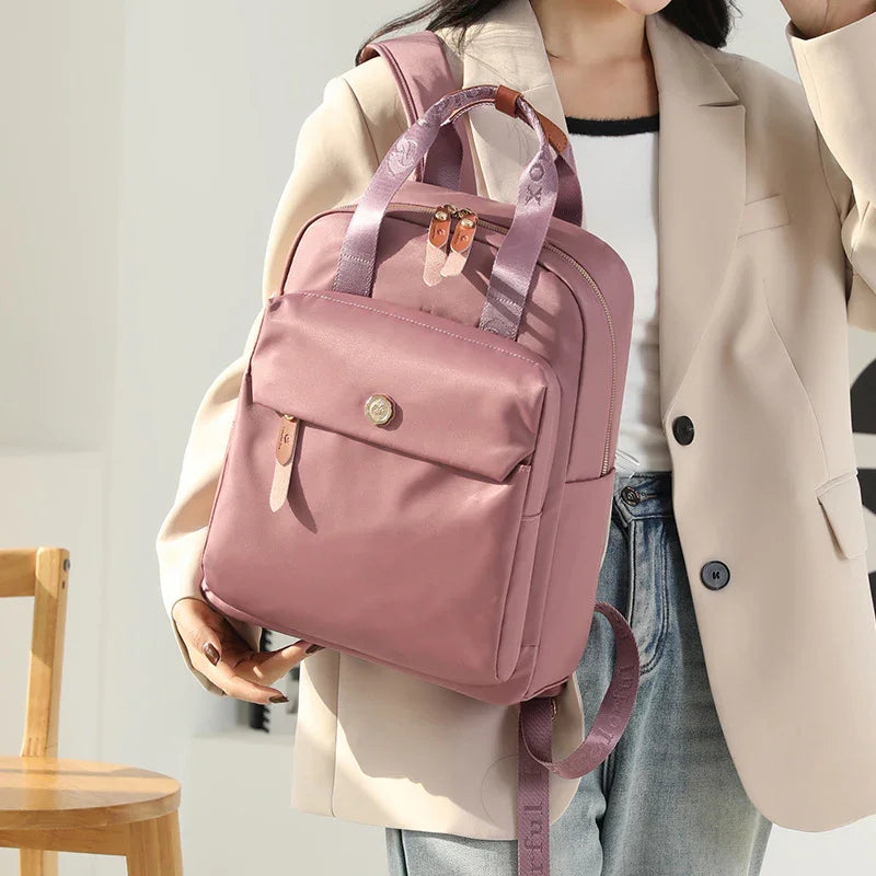 Woman wearing beige blazer and jeans holding pink nylon backpack with front pocket and padded straps