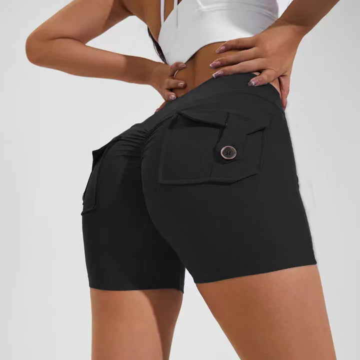 Woman wearing black high-waisted ruched biker shorts with buttoned back pockets and white crop top