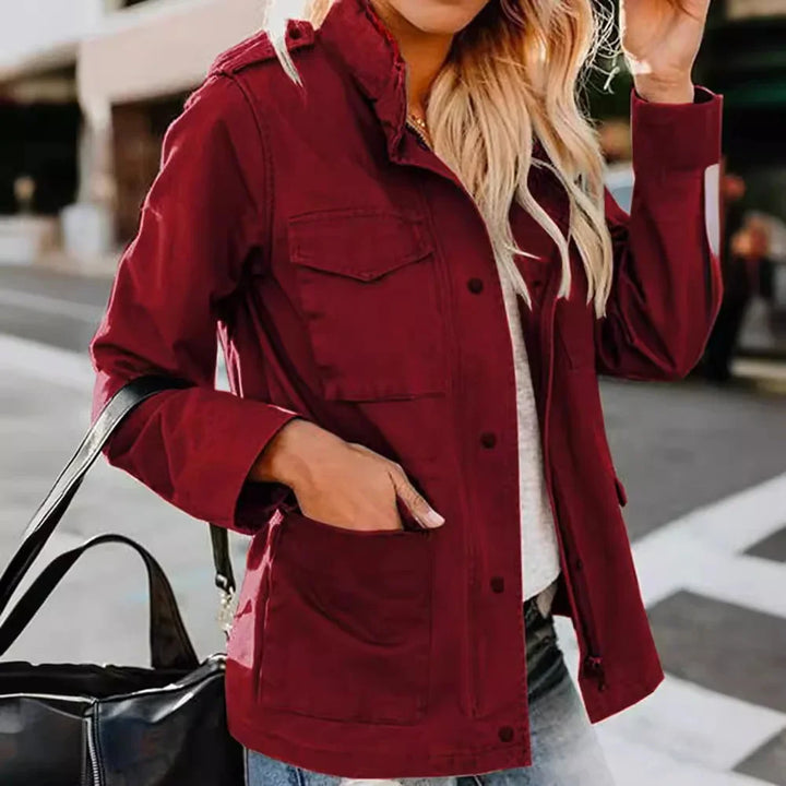 Woman wearing a stylish burgundy jacket with front pockets, paired with blue jeans and carrying a black handbag