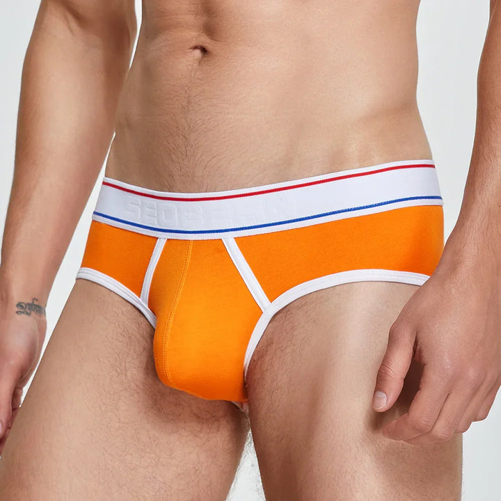 Close-up of male model wearing bright orange briefs with white waistband and trim