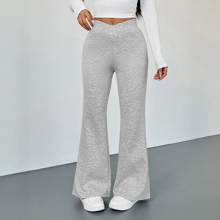 Woman wearing high-waisted gray flare pants with crossover waistband and white crop top